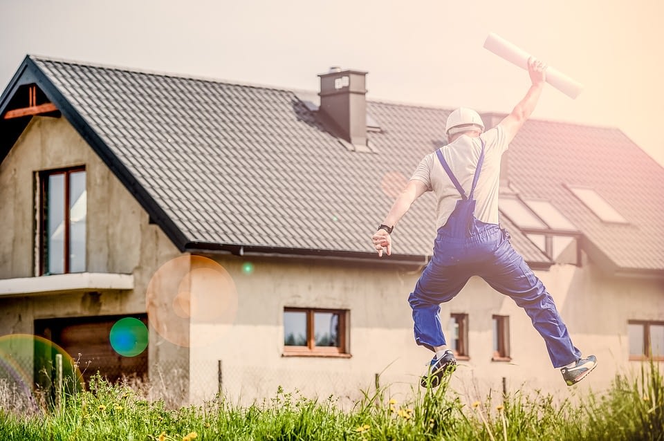 man jumping with house in background